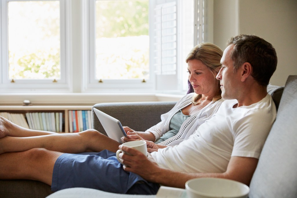 Ein Paar sitzt auf dem Sofa und schaut gemeinsam auf einen Laptop